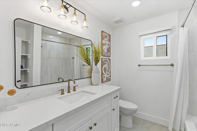 a bathroom with a double vanity sink toilet and mirror