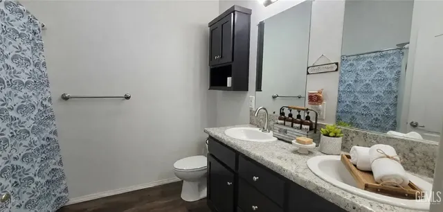 a bathroom with a granite countertop sink and a toilet