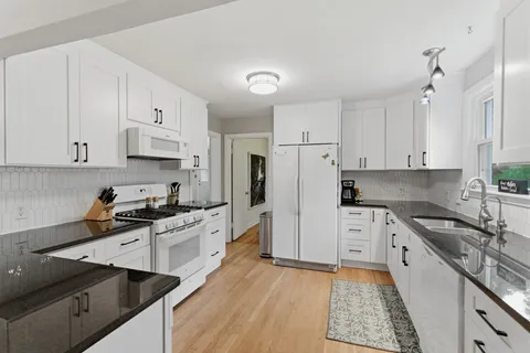 a kitchen with granite countertop a sink stove and refrigerator