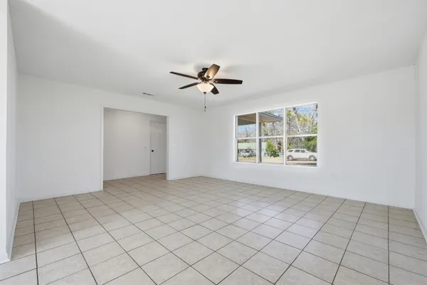 an empty room with windows and ceiling fan