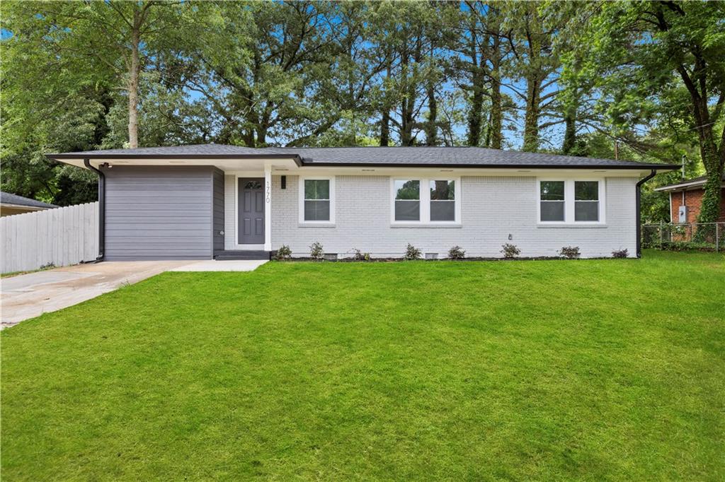 a front view of house with yard and trees in the background