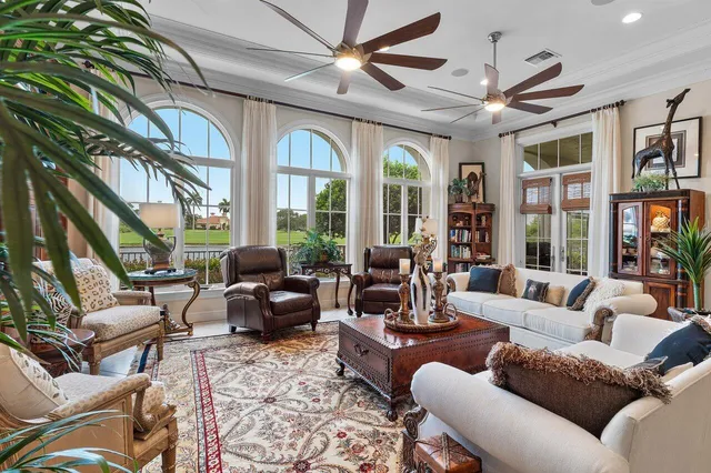 a living room with furniture a ceiling fan and a large window