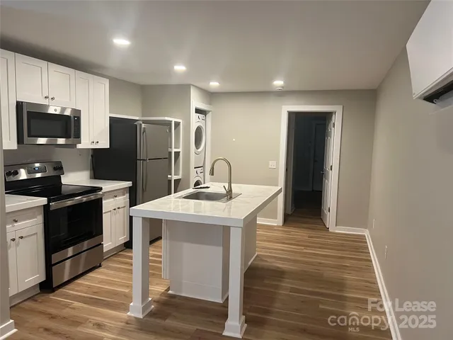 a kitchen with a sink a refrigerator and a stove top oven with wooden floor