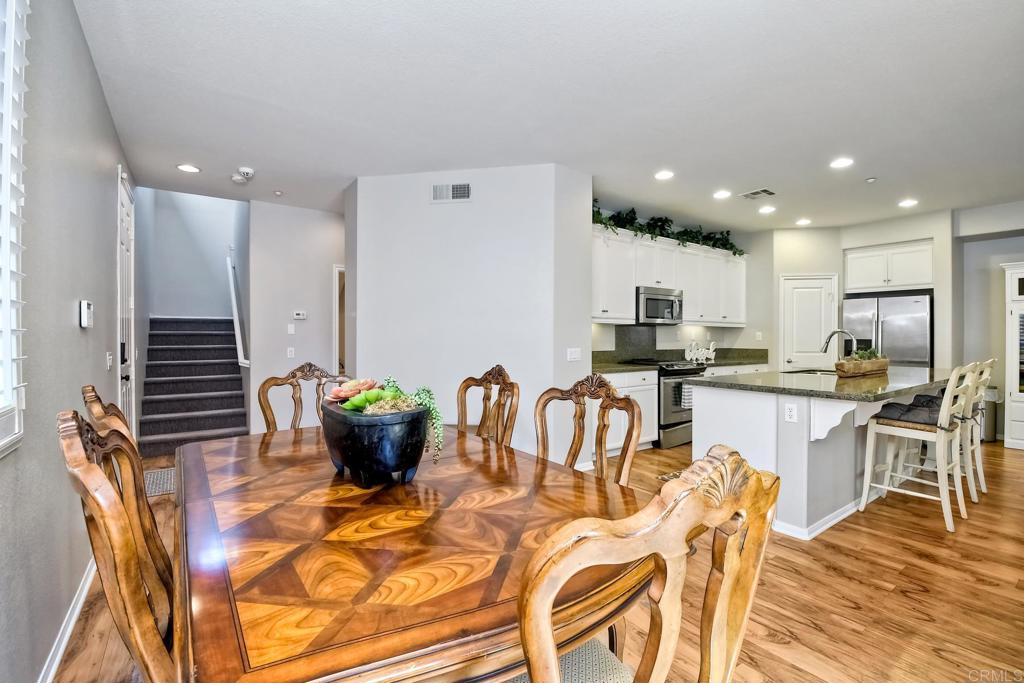 2256 Flatiron Way San Marcos, CA 92078 - Photo 8 of 22 a kitchen with stainless steel appliances kitchen island granite countertop a refrigerator a stove a sink a dining table and chairs with wooden floor