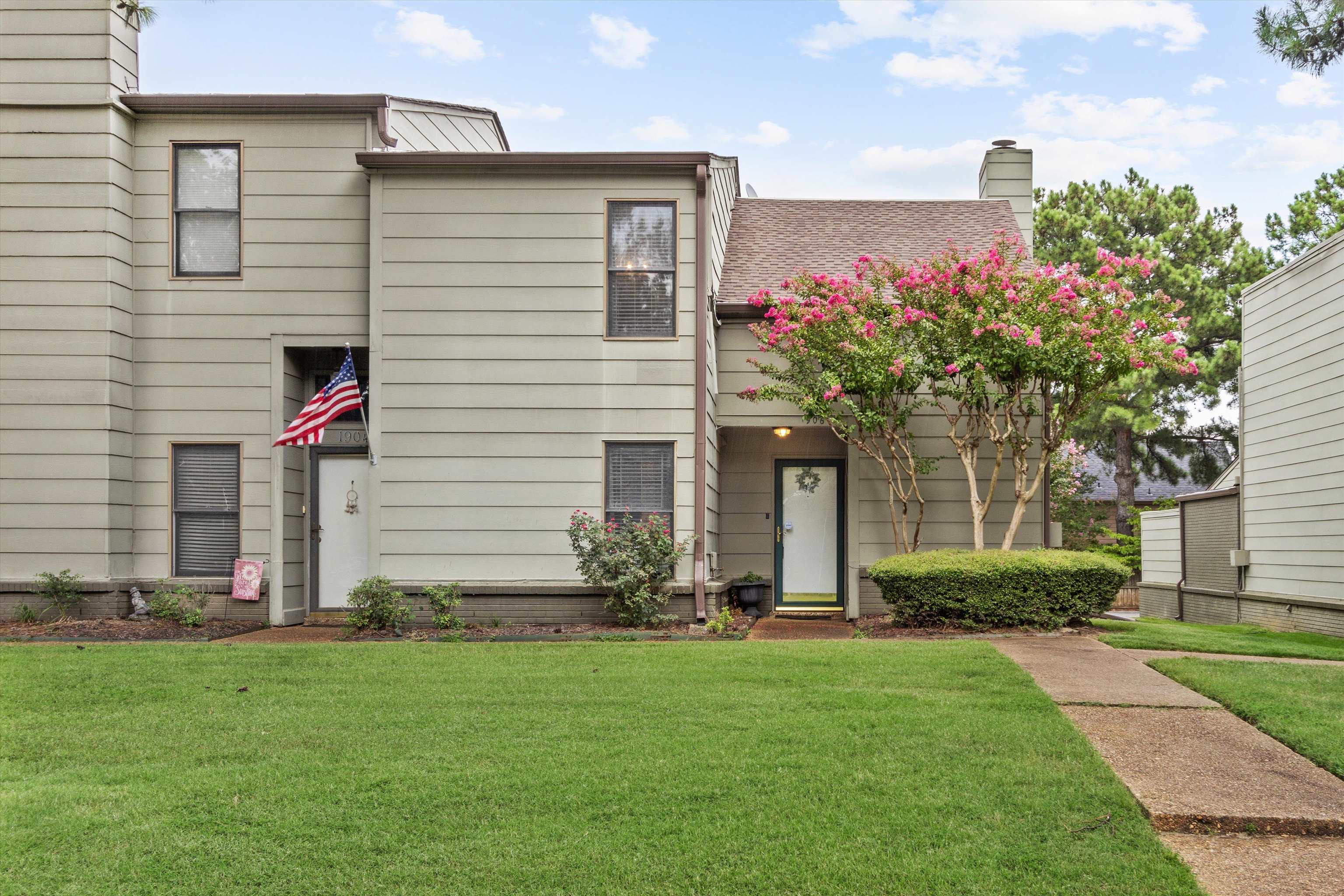 1906 Allenby Road, Unit 16 Germantown, TN 38139 - Photo 1 of 31 Wood siding exterior with a shingled roof, manicured lawn, and mature flowering tree