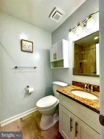 a bathroom with a granite countertop toilet sink and mirror