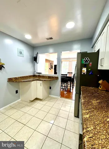 a large kitchen with stainless steel appliances kitchen island granite countertop a refrigerator and a sink