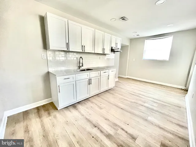 a kitchen with stainless steel appliances granite countertop a sink and cabinets with wooden floor