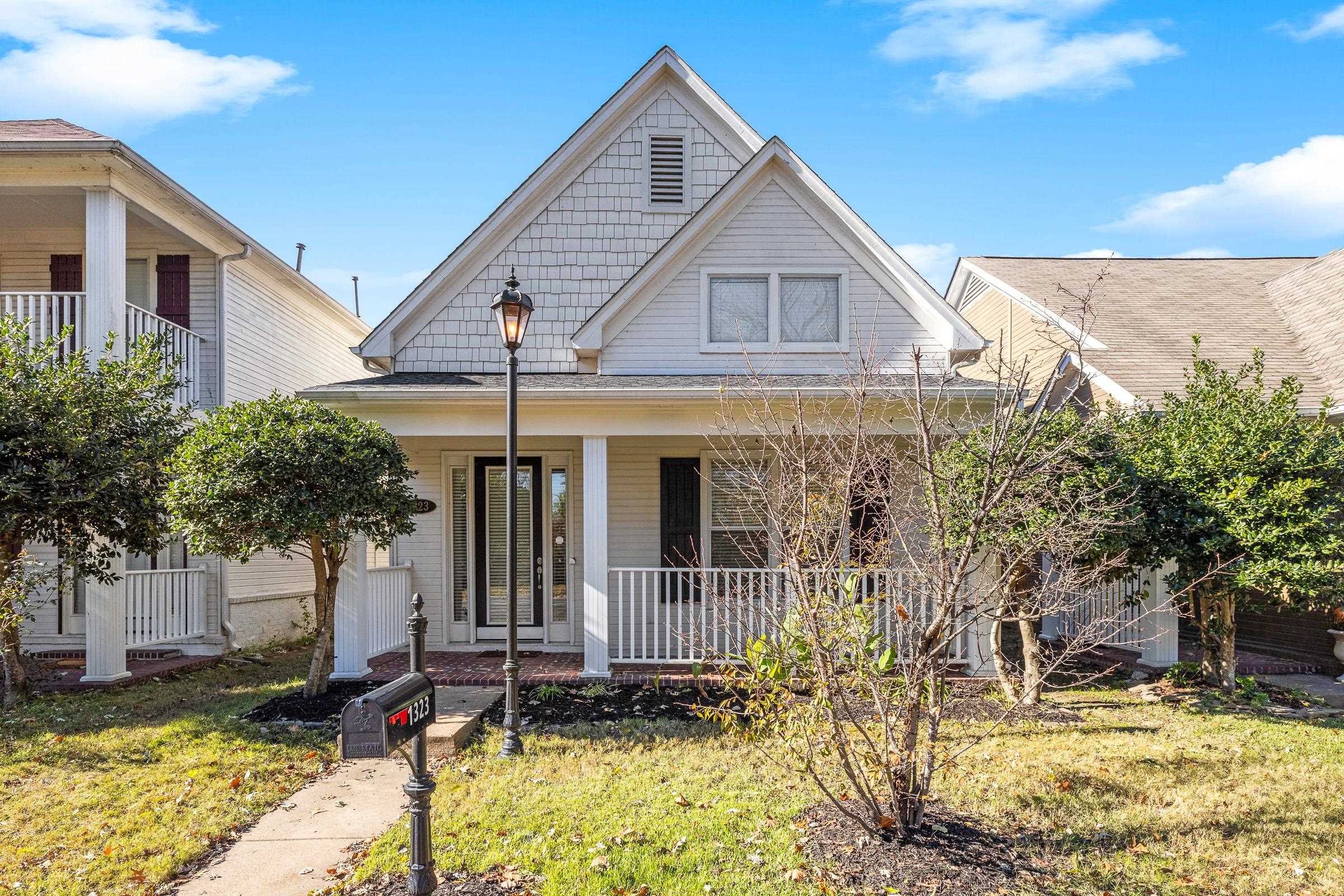 a view of a house with a small yard plants and large tree