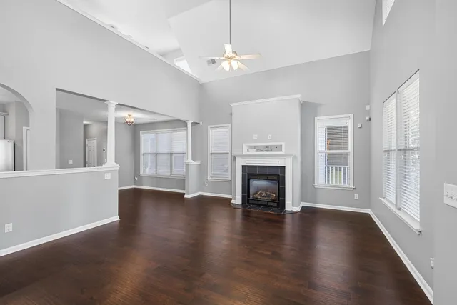 a view of an empty room with wooden floor and a fireplace