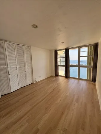 a view of an empty room with a window and wooden floor