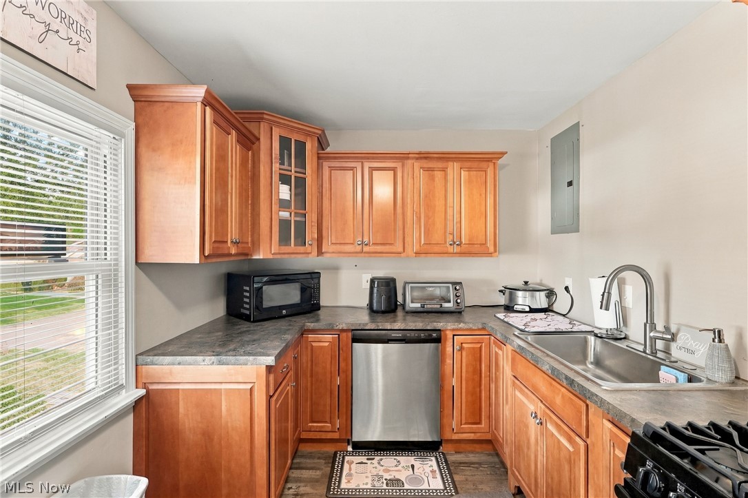 1875 Perth Road Madison, OH 44057 - Photo 6 of 48 Wood-finish cabinetry with crown molding, stainless steel dishwasher, stainless steel sink with a gooseneck faucet, and wood-finish flooring
