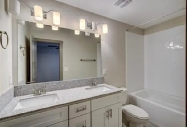 a bathroom with a granite countertop sink a toilet and a bathtub