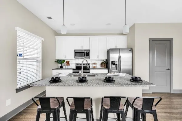 a kitchen with granite countertop white cabinets and stainless steel appliances