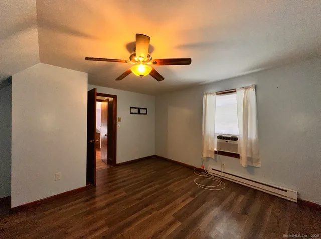an empty room with wooden floor chandelier fan and windows