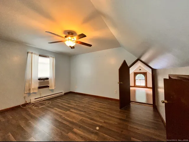 a view of an empty room with window and wooden floor