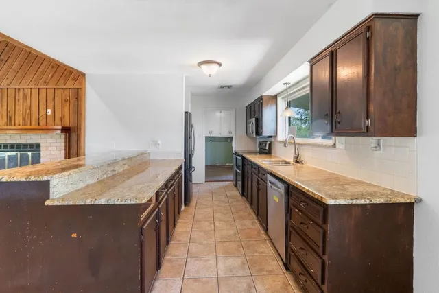 a large kitchen with granite countertop a sink and cabinets