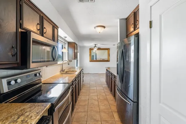 a kitchen with stainless steel appliances granite countertop a refrigerator a stove and a sink with wooden floor