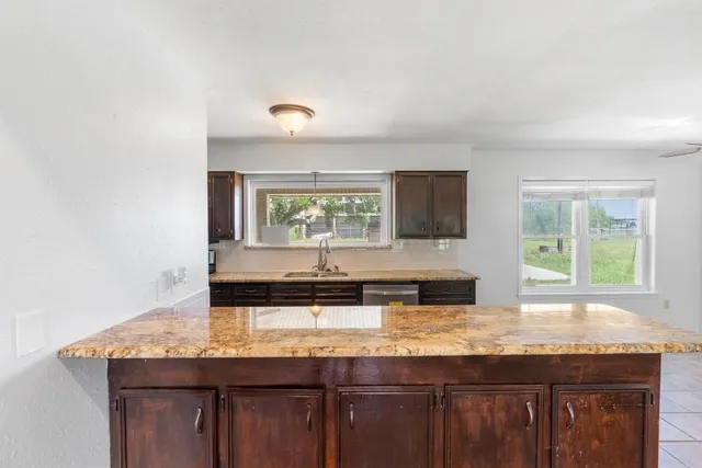 a kitchen with granite countertop a stove a sink and a wooden cabinets