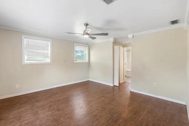 an empty room with wooden floor fan and windows