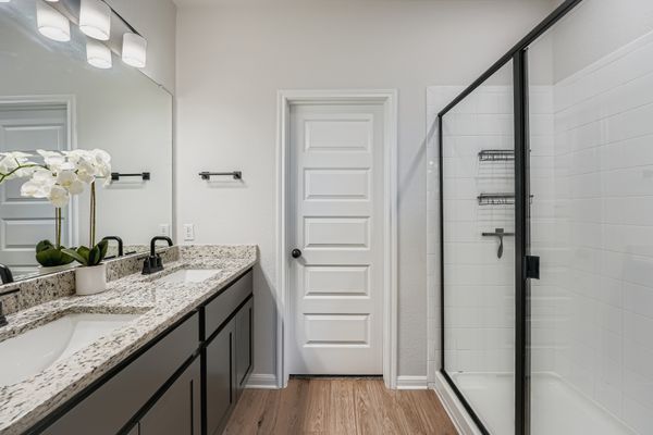 148 Gullivers Drive Elgin, TX 78621 - Photo 11 of 21 Bathroom featuring double vanity, a stall shower, and light wood-style floors