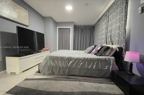 a spacious bedroom with a bed and a flat screen tv