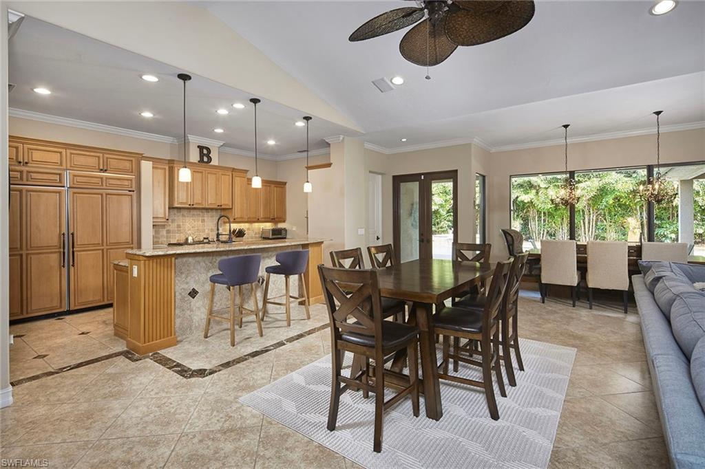 1900 Tiller Terrace Naples, FL 34102 - Photo 11 of 46 a kitchen with stainless steel appliances kitchen island granite countertop a table chairs and a refrigerator