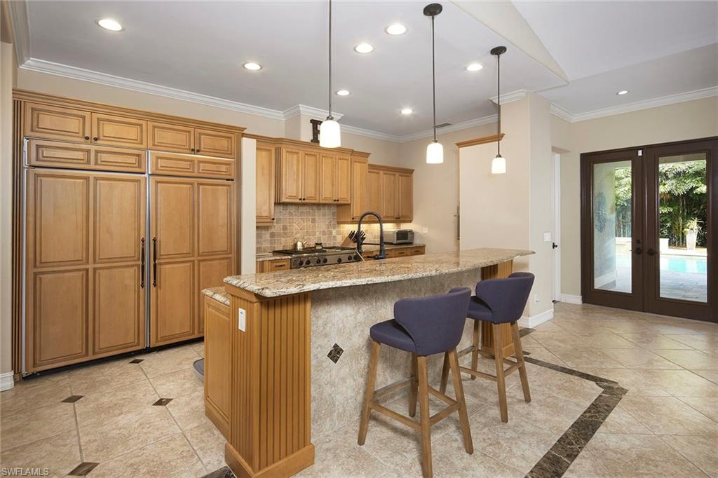 1900 Tiller Terrace Naples, FL 34102 - Photo 12 of 46 a kitchen with kitchen island granite countertop wooden cabinets and a refrigerator