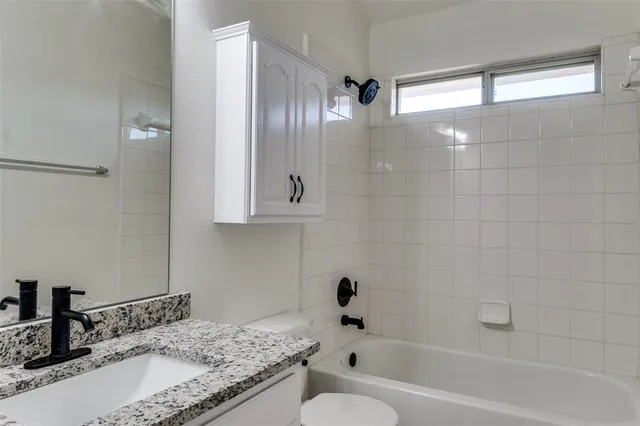 a bathroom with a granite countertop sink a toilet and bathtub