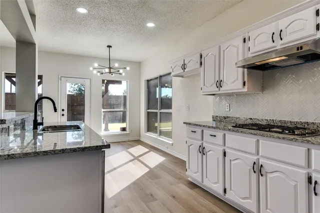 a kitchen with granite countertop a stove a sink a refrigerator and window