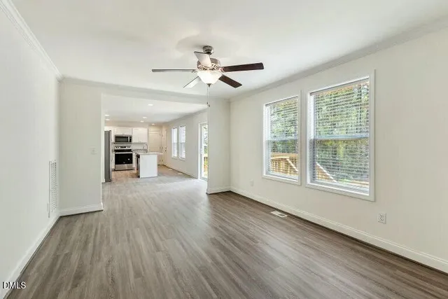 a view of an empty room with a window and wooden floor