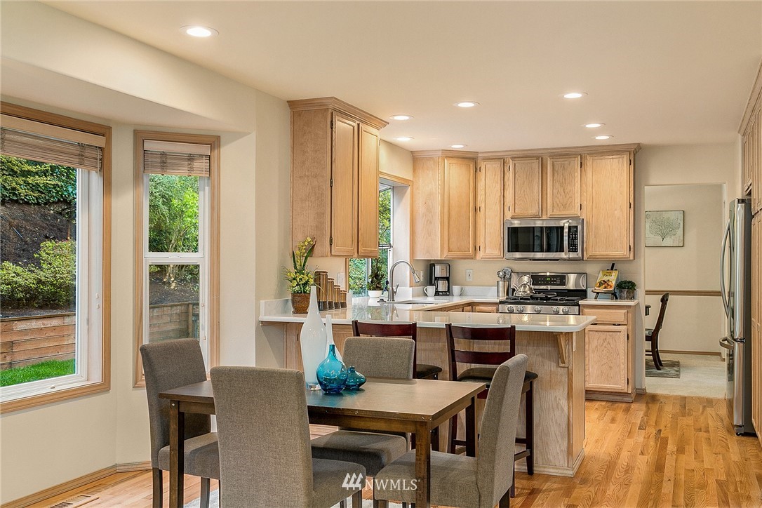 8515 Northeast 176th Street Bothell, WA 98011 - Photo 6 of 25 a kitchen with stainless steel appliances granite countertop a stove top oven a sink dishwasher a dining table and chairs with wooden floor