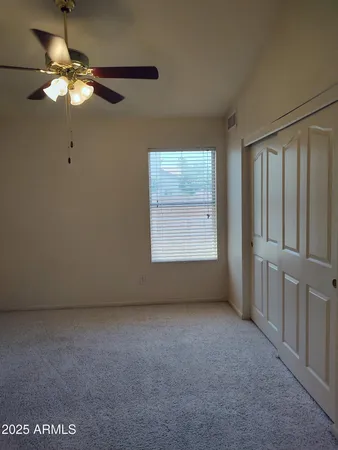 an empty room with a chandelier fan and windows