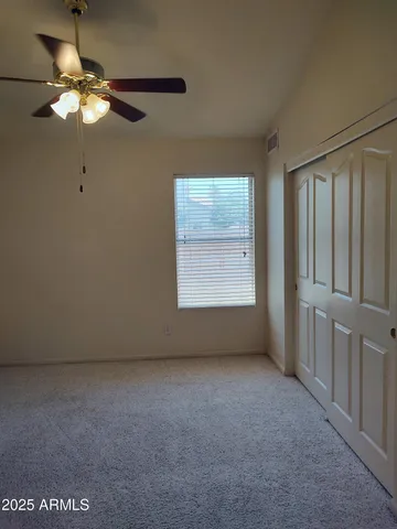 an empty room with a chandelier fan and windows