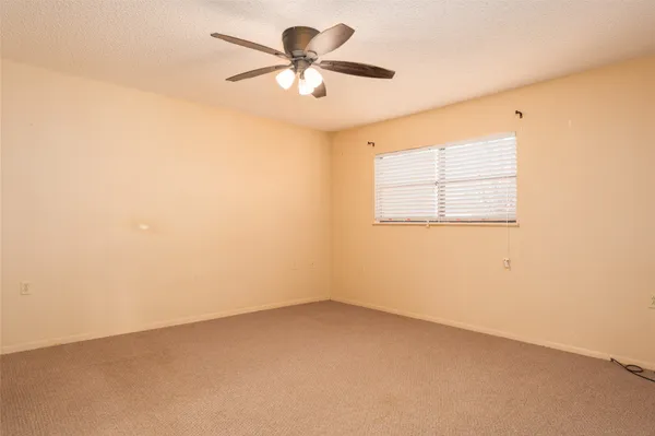 an empty room with a window and a fan