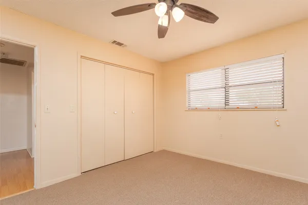 en empty room with windows and ceiling fan
