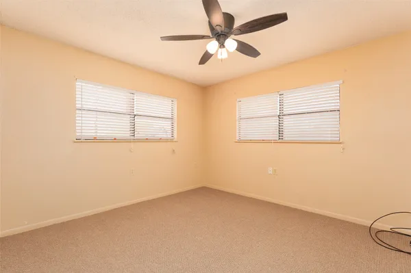 an empty room with a window and a fan