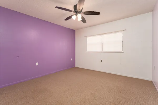 an empty room with a window and a ceiling fan
