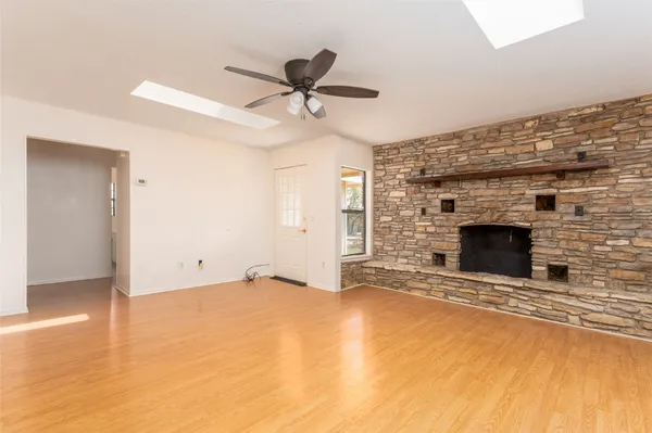 a view of empty room with a fireplace and a ceiling fan