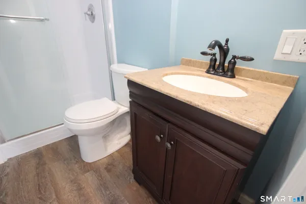 a bathroom with a granite countertop sink toilet and mirror