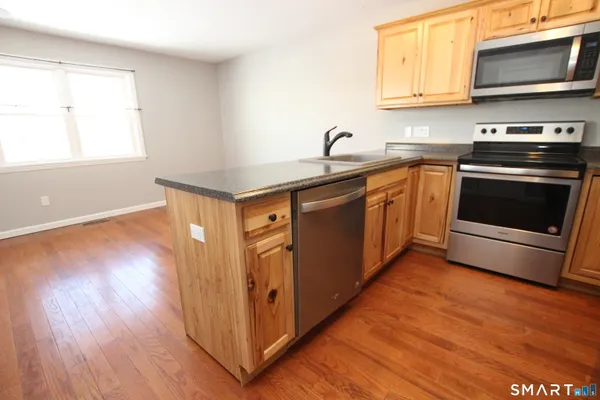 a kitchen with stainless steel appliances granite countertop a sink a stove a microwave and wooden floors