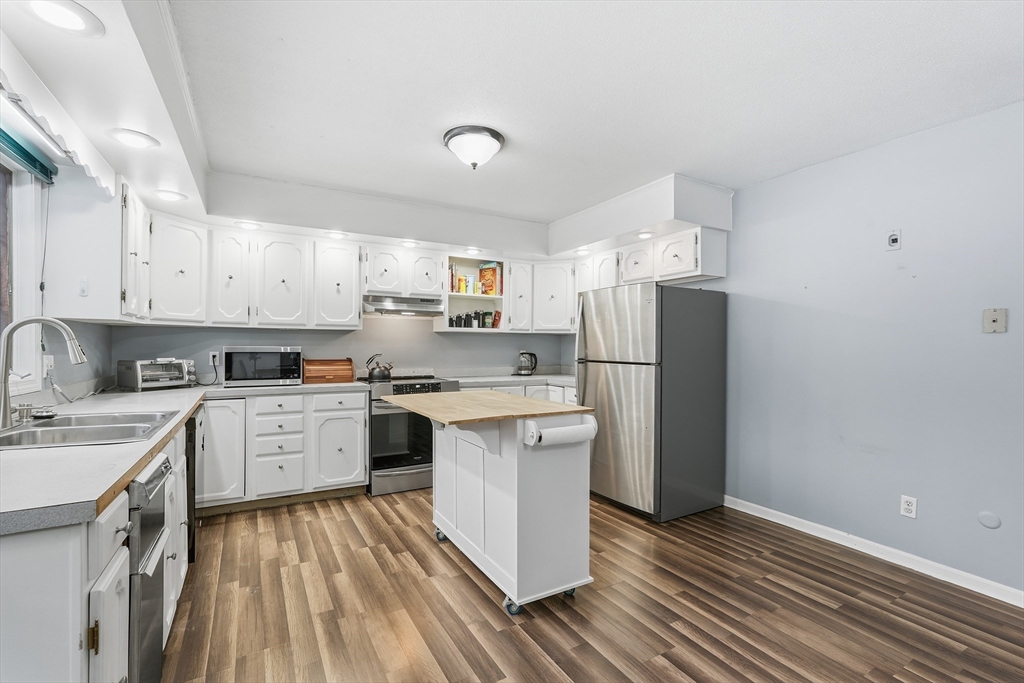 32 Homestead Avenue Greenfield, MA 01301 - Photo 14 of 41 a kitchen with a sink dishwasher a refrigerator oven a sink dishwasher and white cabinets with wooden floor