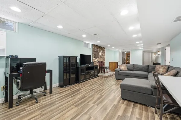 a living room with furniture a flat screen tv and a refrigerator