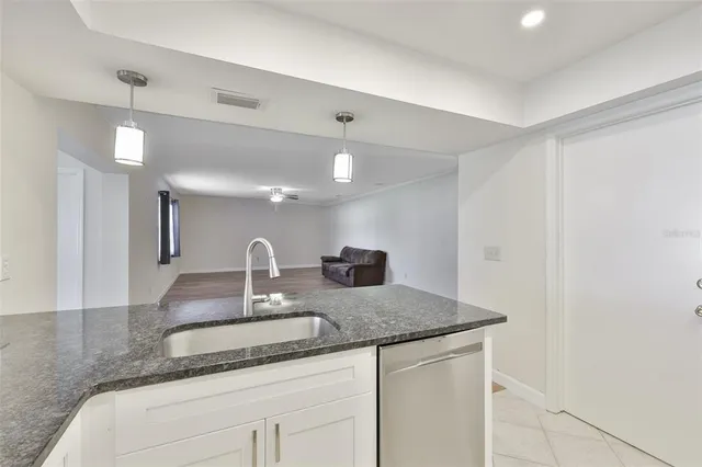 a kitchen with granite countertop a sink and white cabinets