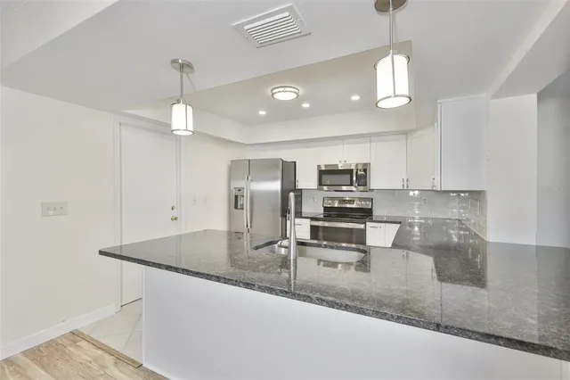 a kitchen with stainless steel appliances granite countertop a sink a stove and a refrigerator