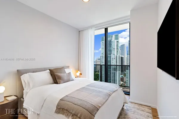 a bedroom with a large bed and a flat tv screen on dresser