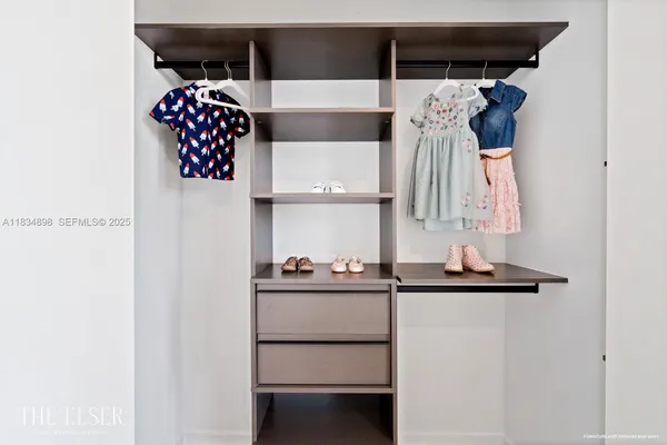 a view of walk in closet with clothes and shoes