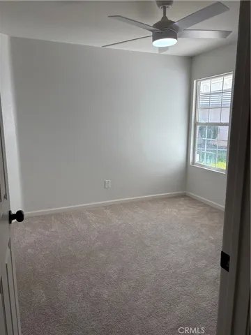 an empty room with windows and fan