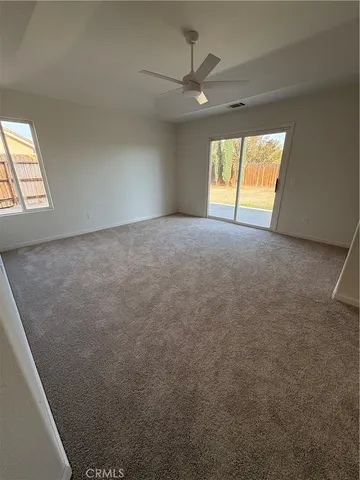 an empty room with windows and fan