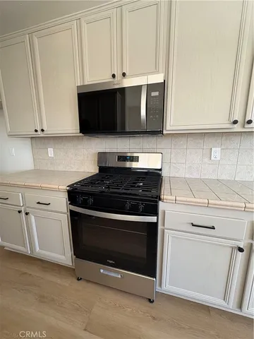 a kitchen with stainless steel appliances granite countertop white cabinets and a stove